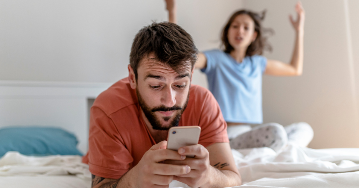 Žena vyzerá nahnevane, zatiaľ čo muž je zaujatý mobilom a ignoruje ju.